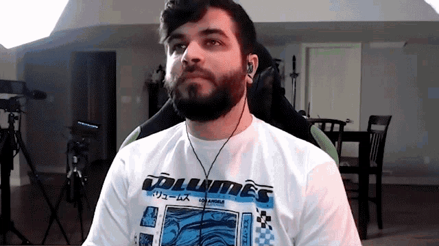 a man with a beard is wearing a white shirt with the word volumes on it