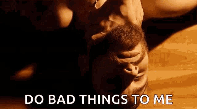 a man with a beard is laying on his back with the words `` do bad things to me '' written below him .