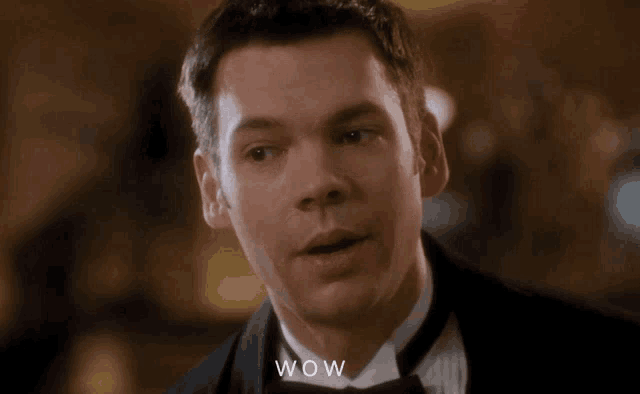 a man in a tuxedo says wow in a close up of his face