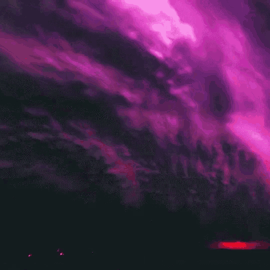 a purple and pink cloudy sky with a sunset in the background