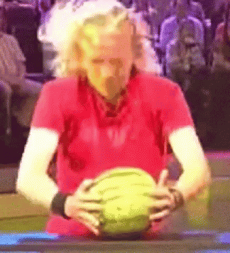 a man in a red shirt holds a watermelon