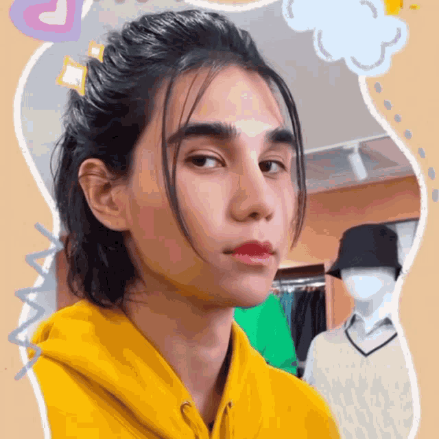 a young man wearing a yellow hoodie is looking at the camera