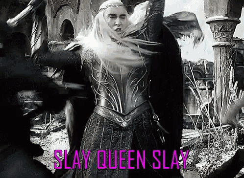 a woman in armor is standing in front of a group of people with her arms up .