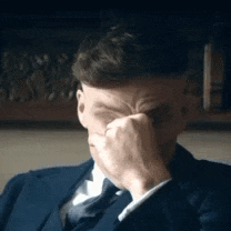 a man in a suit and tie is crying while covering his face with his hand .