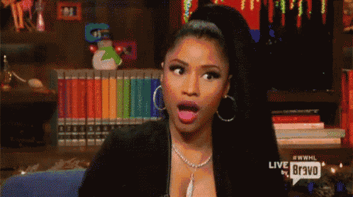 a woman with a surprised look on her face is sitting in front of a bookshelf with books .