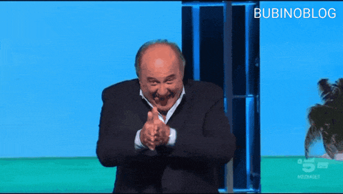 a man in a suit is clapping his hands in front of a screen that says bubinoblog on it