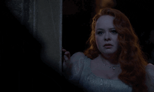 a woman with red hair and a white dress is standing in the dark
