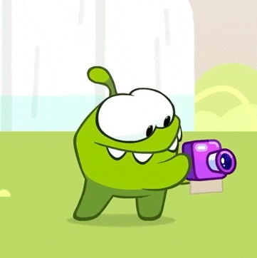 a green cartoon character is holding a purple camera in his hand