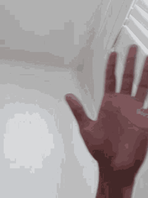 a close up of a person 's hand reaching out towards a white wall .