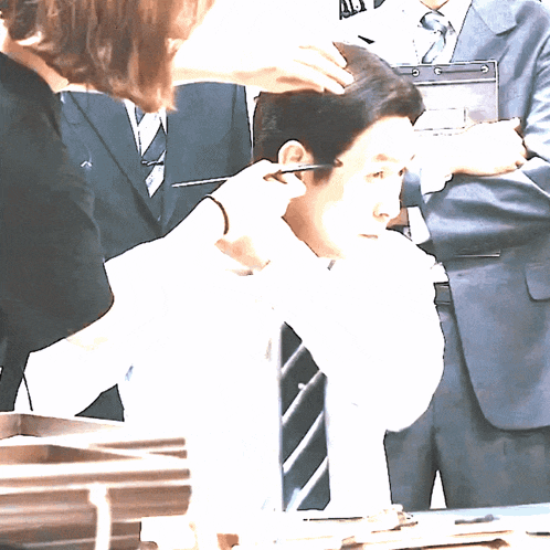 a man in a suit has his hair cut by a woman