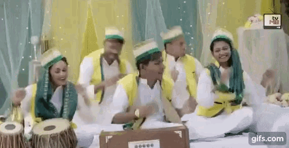 a group of people are sitting on the floor playing drums and singing together .