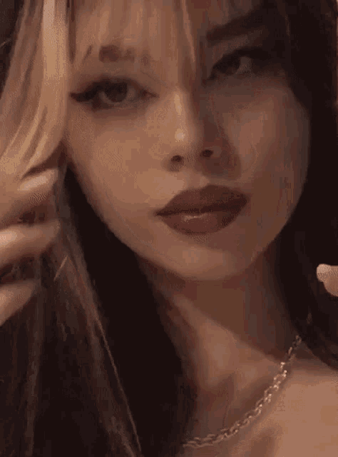 a close up of a girl 's face with a necklace and red lips .