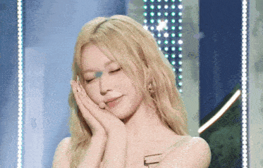 a woman with blonde hair is covering her face with her hand