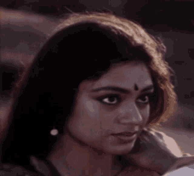 a woman with a bindi on her forehead smiles