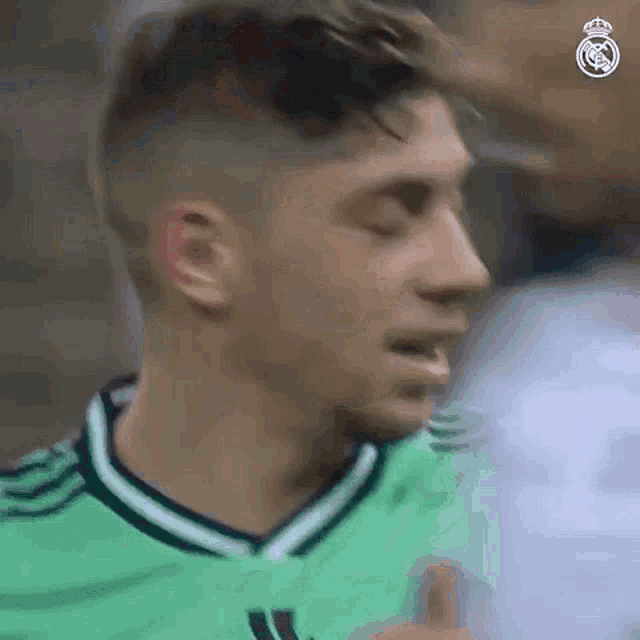 a soccer player in a green jersey is giving a thumbs up sign .