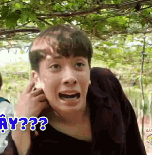 a young man is making a funny face with the words " why ?? " behind him .