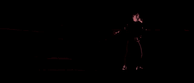 a blurry picture of a man holding a microphone in a dark room .