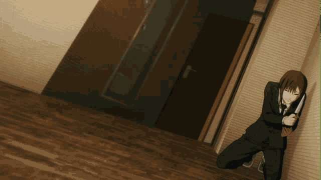 a man in a suit is kneeling down holding a knife in a hallway