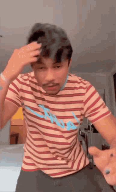 a man wearing a striped shirt with a blue letter a on it