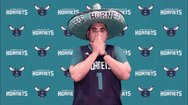 a man wearing a sombrero stands in front of a backdrop that says charlotte hornets