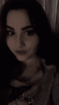 a close up of a woman 's face with a watch on her wrist