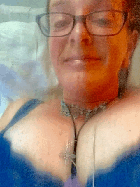 a woman wearing glasses and a blue bra smiles for the camera