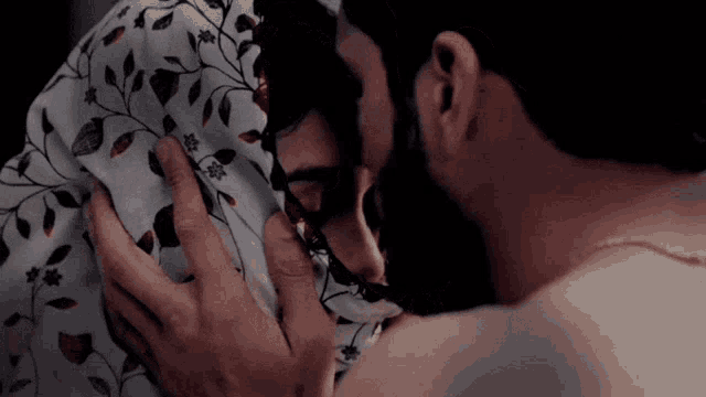 a man and a woman are kissing in bed under a blanket .