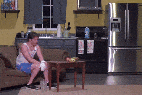 a man sits on a couch in front of a stainless steel refrigerator in a kitchen