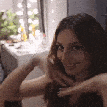 a woman is smiling and touching her hair in front of a mirror in a dressing room .