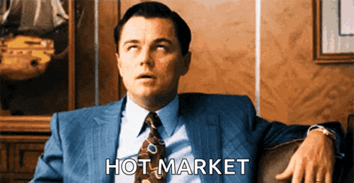 a man in a suit and tie is sitting in a chair with the words hot market written in front of him