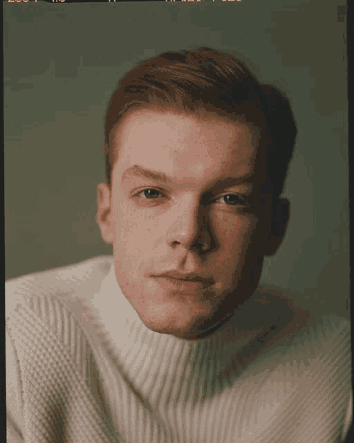 a man with red hair and freckles wearing a white turtleneck sweater