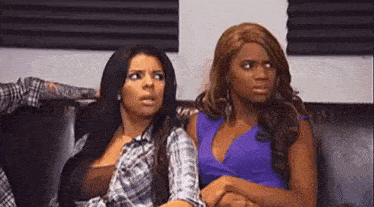 two women are sitting next to each other on a couch .