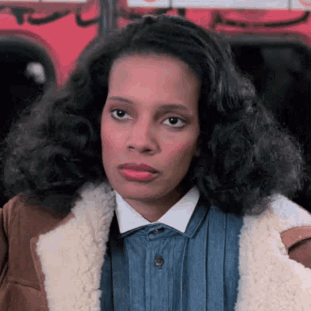 a woman with curly hair wearing a denim shirt and a fur coat .