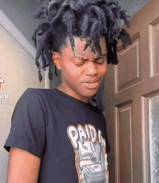 a young man with dreadlocks is wearing a panda t-shirt and making a funny face .