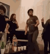 a group of people are dancing in a living room with a fanta bottle in the foreground
