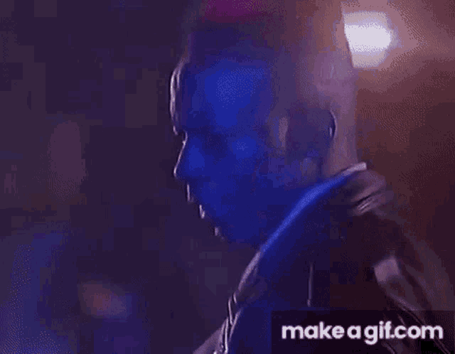 a close up of a man 's face in a dark room with blue lights behind him .