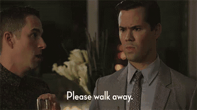 a man in a suit and tie is standing next to another man and asking him to walk away .