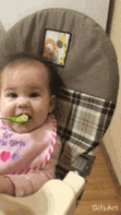 a baby is sitting in a high chair eating food with a spoon