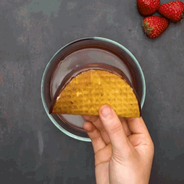 a person is dipping a waffle in chocolate