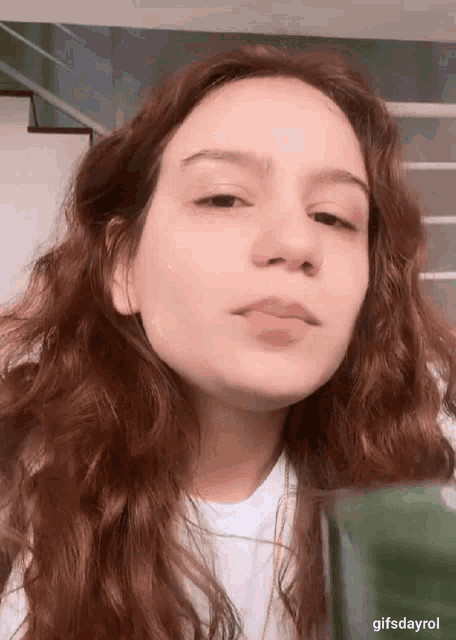 a young woman with red hair is making a funny face while wearing a white shirt .