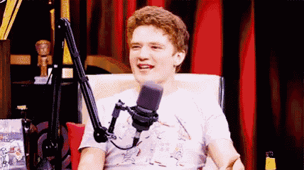a young man is sitting in a chair in front of a microphone .