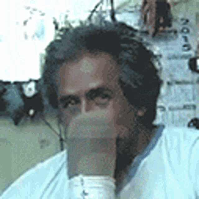 a man in a white shirt is sitting in front of a wall with a calendar .