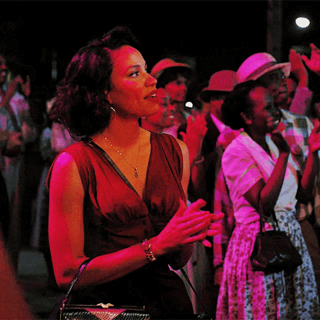 a woman in a red dress is standing in a crowd