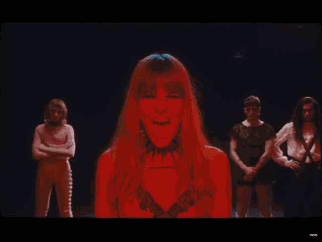 a group of people are standing in a dark room and one of them has a choker around her neck