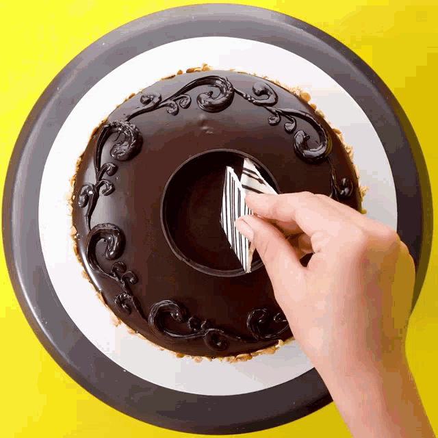a person is decorating a chocolate cake with a striped pattern