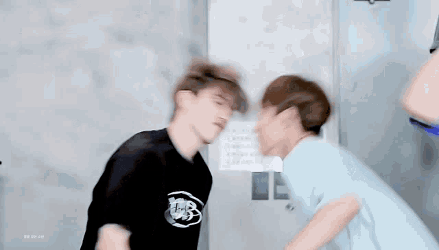two men are standing next to each other and kissing each other in a room .