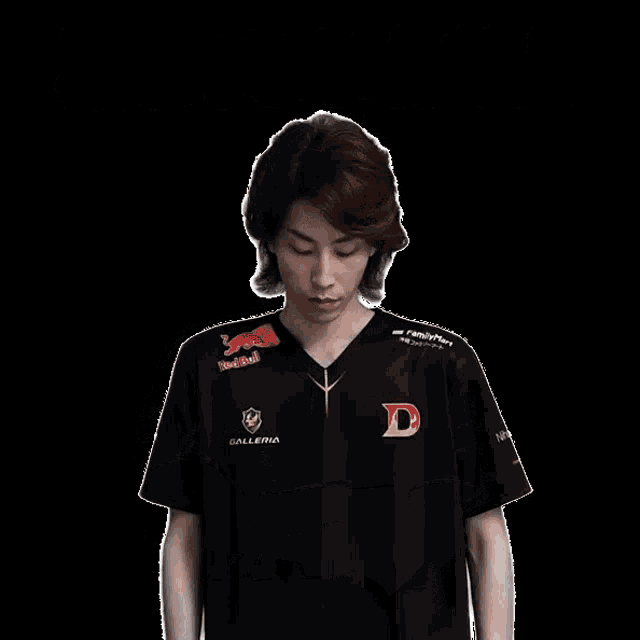 a man wearing a black shirt with the letter d on it stands with his arms crossed
