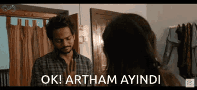 a man and a woman are standing next to each other in a room and the woman is saying ok .