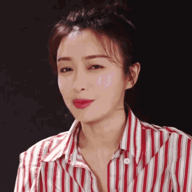 a woman is wearing a red and white striped shirt and making a funny face .