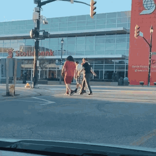 a group of people are crossing the street in front of a building that says scotiabank